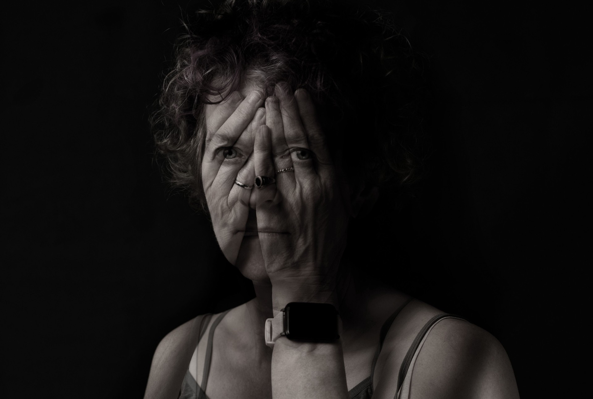 Portrait of a woman with her hands over her face.