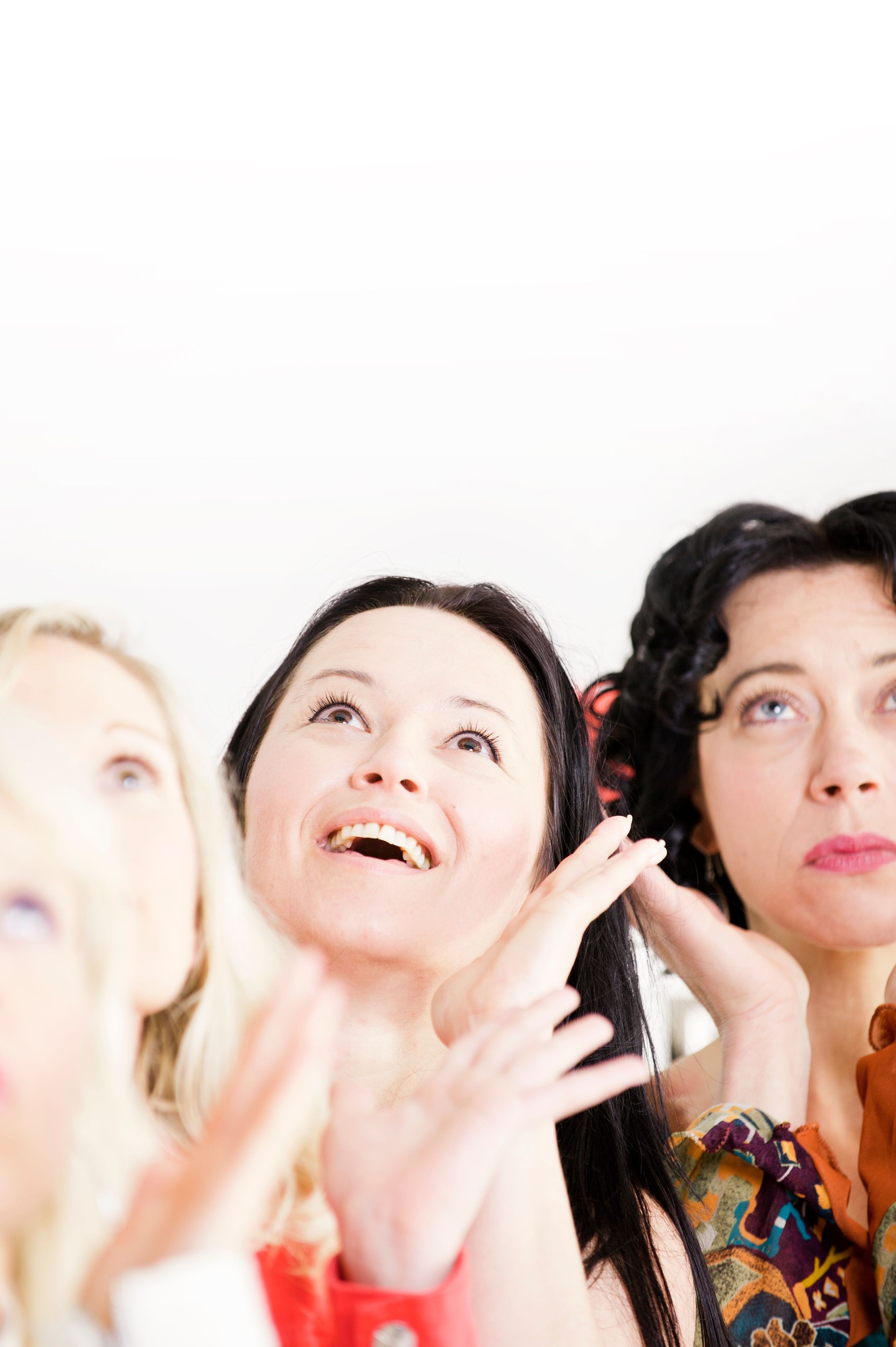 Three happy young women smile up excitedly at something unseen